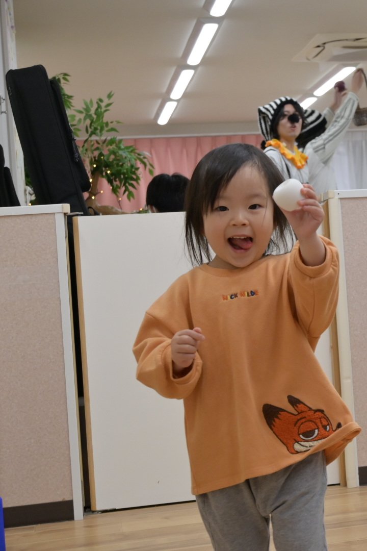 白いりんごを手に、こちらを見て笑う園児